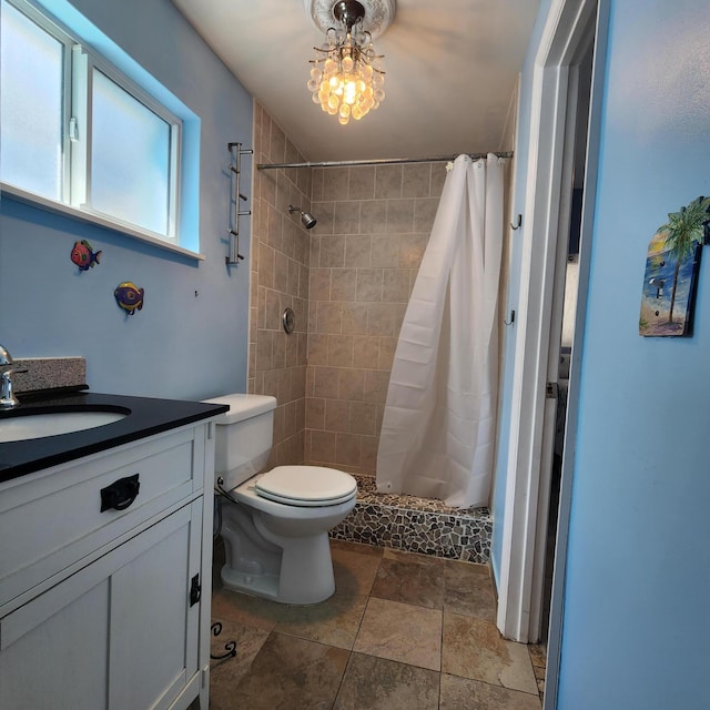 full bath featuring stone finish floor, a shower stall, toilet, and vanity