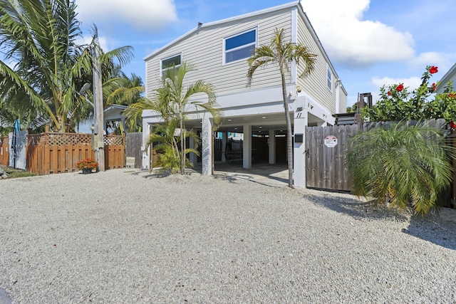 view of front facade featuring a carport, driveway, fence, and a gate