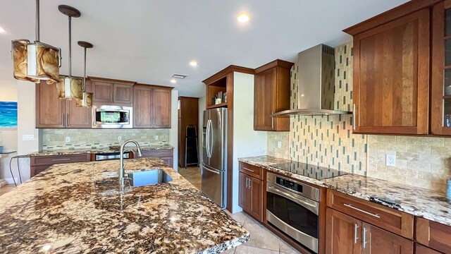 kitchen featuring stone countertops, sink, hanging light fixtures, stainless steel appliances, and wall chimney exhaust hood