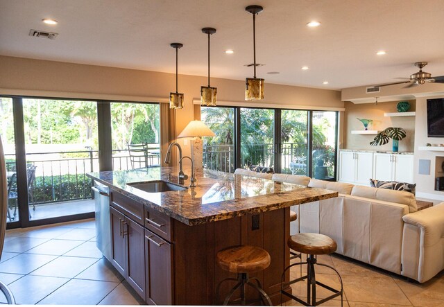 kitchen featuring sink, a breakfast bar area, dishwasher, pendant lighting, and dark stone counters