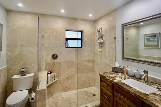 bathroom featuring vanity, a tile shower, and toilet