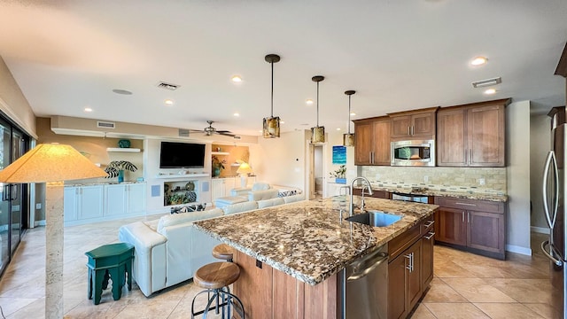 kitchen with a breakfast bar, sink, an island with sink, pendant lighting, and stainless steel appliances