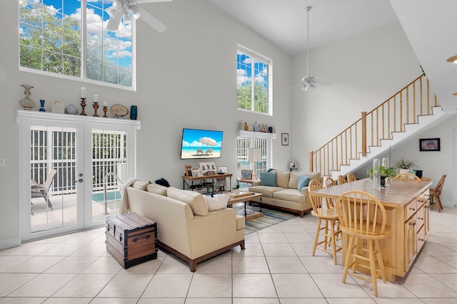 living room featuring light tile patterned flooring, a towering ceiling, ceiling fan, and french doors