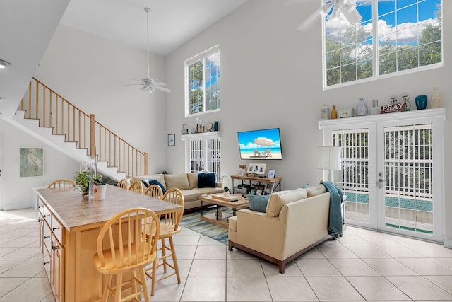 living room featuring light tile patterned floors, french doors, ceiling fan, and a high ceiling