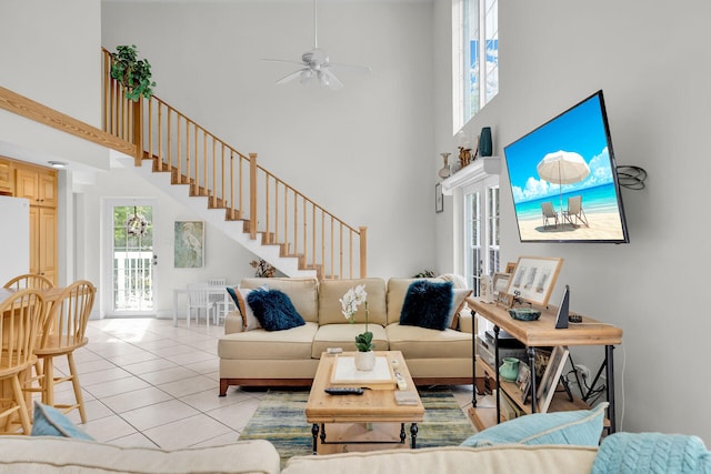 living room featuring light tile patterned flooring, ceiling fan, and a towering ceiling