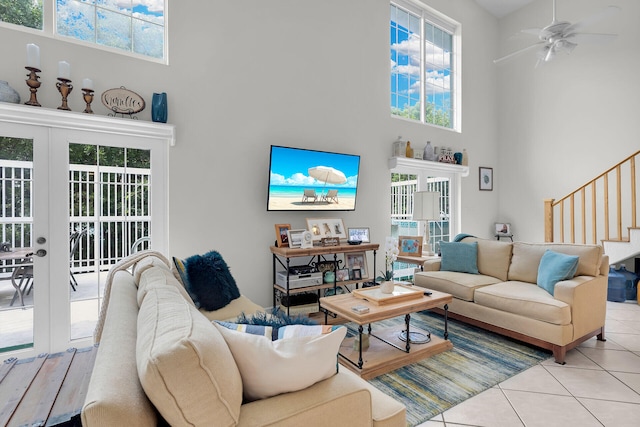 living room featuring plenty of natural light, a towering ceiling, light tile patterned floors, and french doors