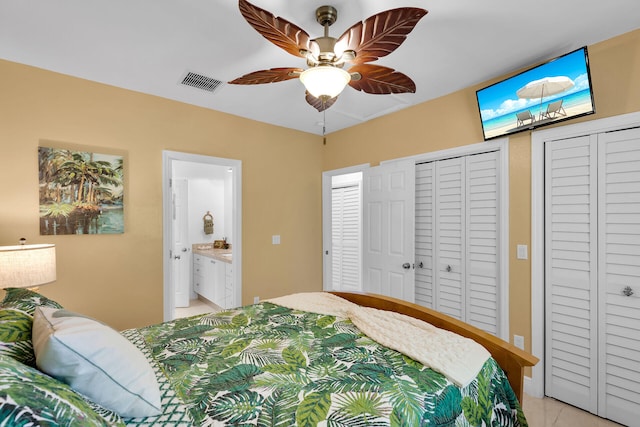 bedroom with two closets, light tile patterned flooring, ceiling fan, and ensuite bathroom