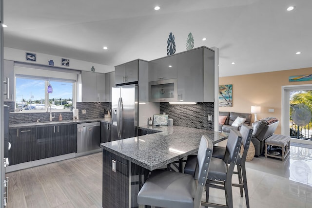 kitchen featuring sink, gray cabinetry, a kitchen breakfast bar, stainless steel appliances, and kitchen peninsula