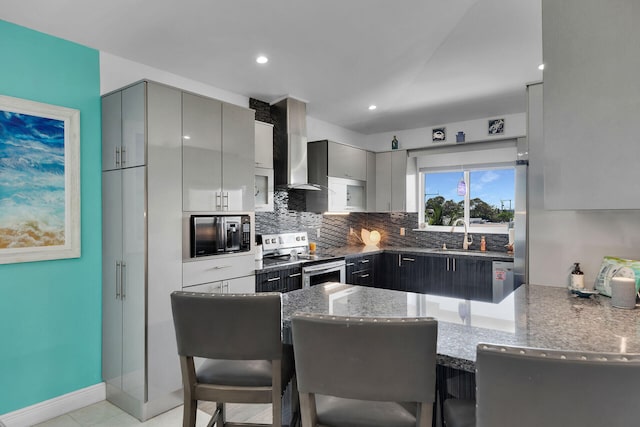 kitchen with gray cabinetry, stainless steel range with electric cooktop, kitchen peninsula, and dark stone countertops