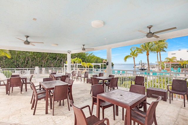 view of patio with a water view and ceiling fan