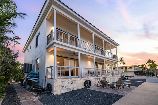 view of front of property featuring ceiling fan, a patio, a balcony, and an outdoor fire pit