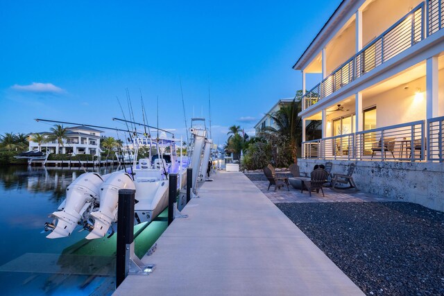 dock area featuring a balcony, a water view, a patio area, and a fire pit