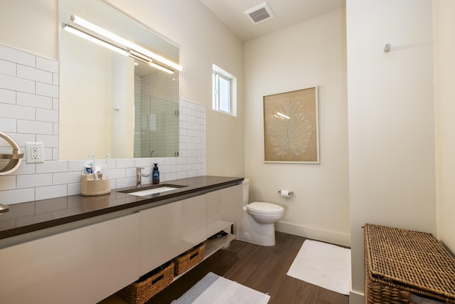 bathroom with toilet, a shower with shower door, tasteful backsplash, wood-type flooring, and vanity