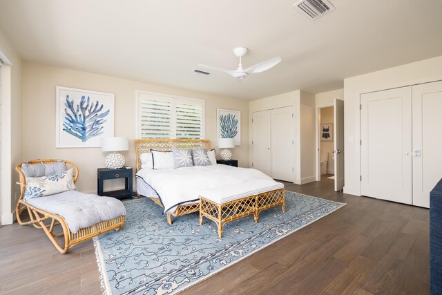 bedroom with dark hardwood / wood-style flooring, ceiling fan, and multiple closets