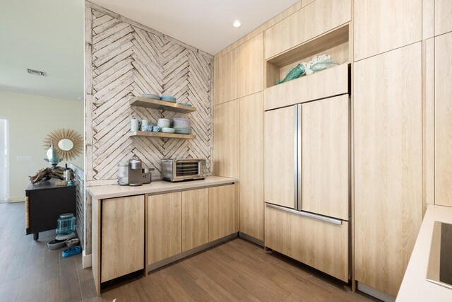 interior space featuring light brown cabinetry, hardwood / wood-style floors, and paneled built in refrigerator