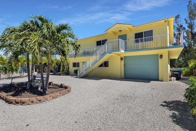 view of front of property featuring gravel driveway, a garage, stairs, and stucco siding