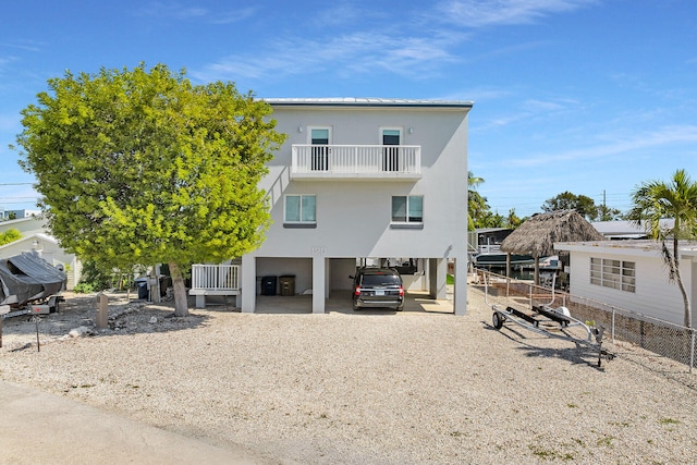 back of house featuring a carport, driveway, a balcony, and stucco siding