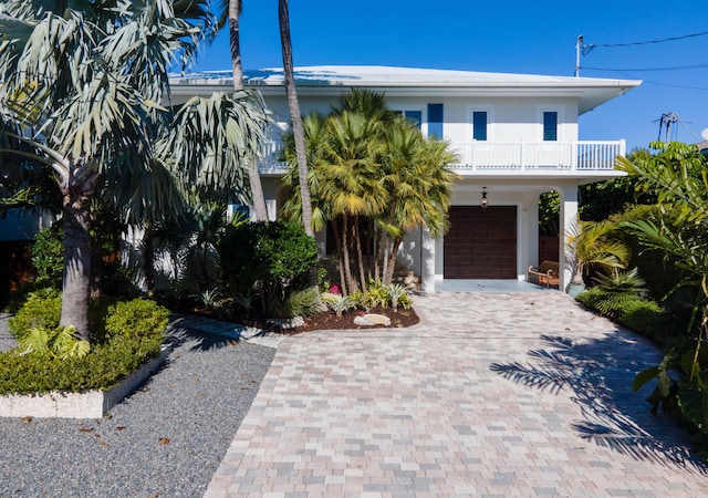 raised beach house featuring a garage and a balcony