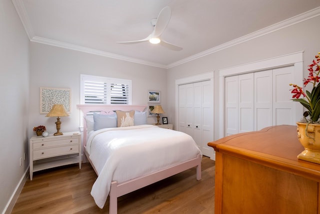 bedroom featuring ceiling fan, ornamental molding, hardwood / wood-style floors, and two closets