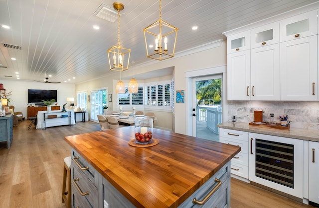 kitchen featuring wood ceiling, hanging light fixtures, white cabinets, wood counters, and beverage cooler