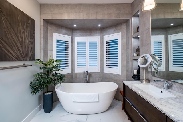 bathroom with vanity, a washtub, and tile walls