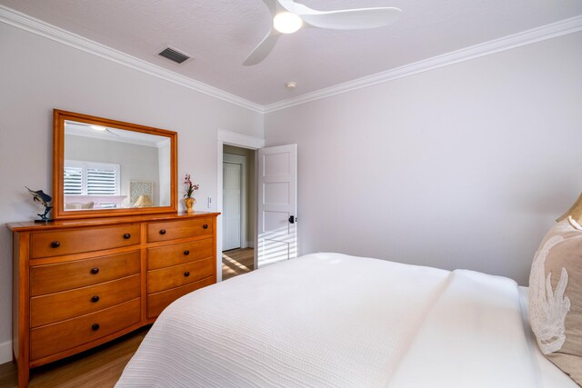 bedroom with hardwood / wood-style floors, ornamental molding, and ceiling fan