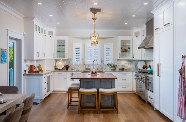 kitchen featuring pendant lighting, high end range, white cabinetry, a kitchen breakfast bar, and a center island