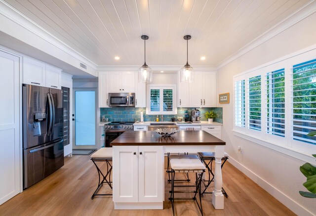 kitchen featuring appliances with stainless steel finishes, pendant lighting, and white cabinets