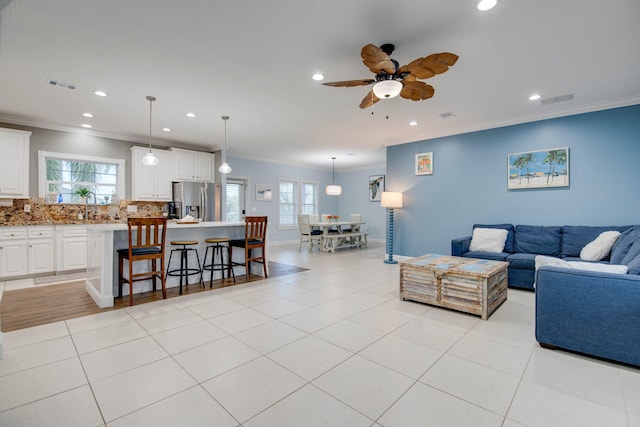 tiled living room with ornamental molding, sink, and ceiling fan