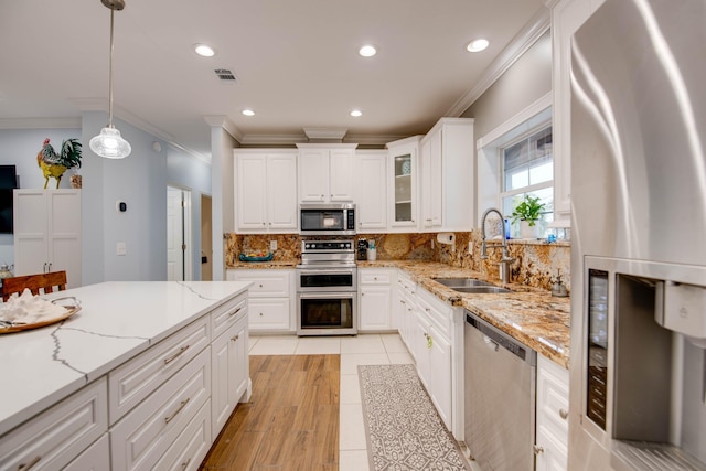 kitchen featuring sink, white cabinetry, hanging light fixtures, stainless steel appliances, and light stone countertops