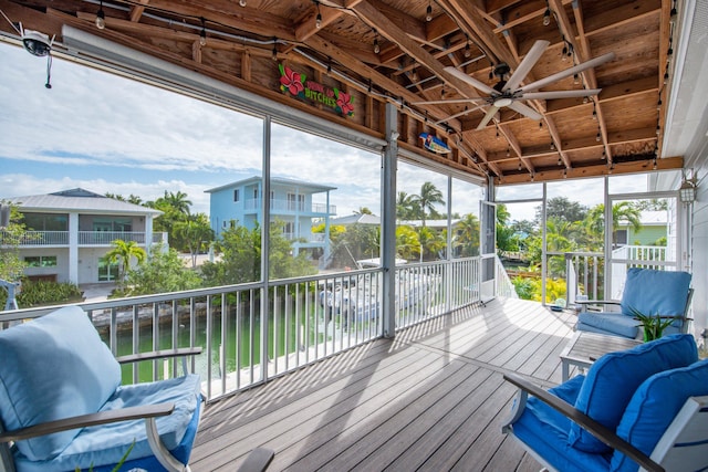 sunroom with a water view, ceiling fan, and a healthy amount of sunlight