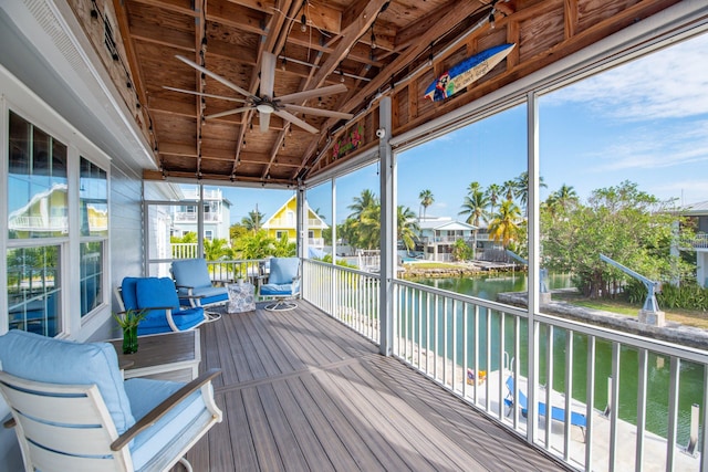 sunroom featuring a water view and ceiling fan