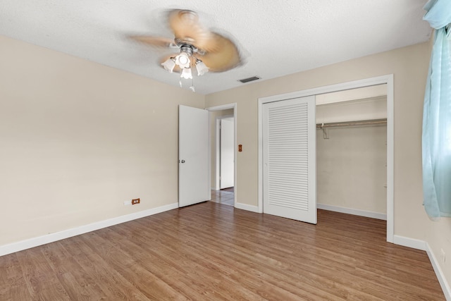 unfurnished bedroom featuring hardwood / wood-style flooring, a closet, ceiling fan, and a textured ceiling