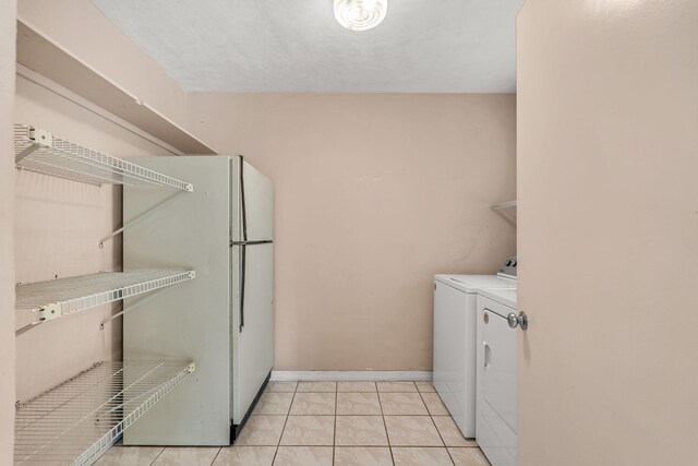 laundry area with light tile patterned floors and washing machine and dryer