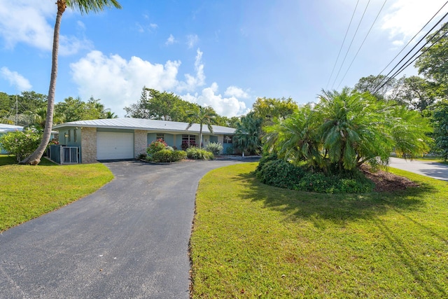 ranch-style home with a garage, a front lawn, and central air condition unit