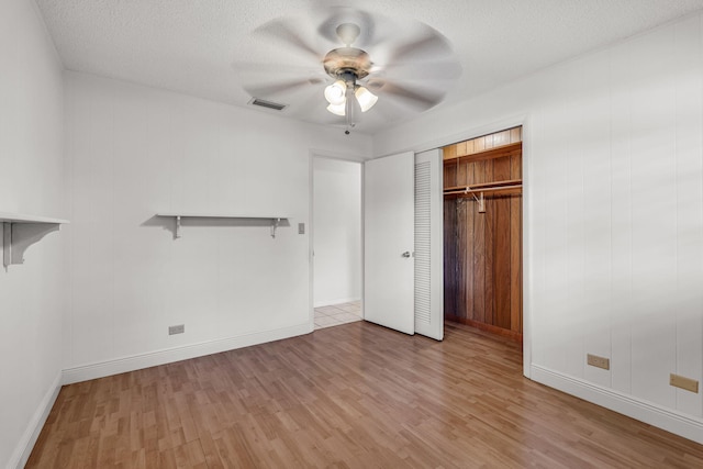 unfurnished bedroom featuring ceiling fan, light hardwood / wood-style floors, a closet, and a textured ceiling