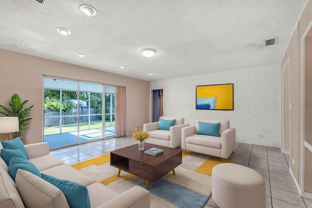 tiled living room featuring brick wall and a textured ceiling