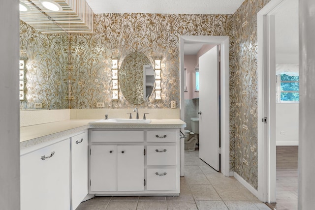 bathroom featuring vanity, toilet, tile patterned flooring, and a textured ceiling