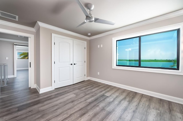 unfurnished bedroom with ornamental molding, hardwood / wood-style floors, ceiling fan, and a closet