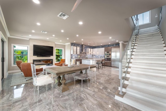 dining area with ornamental molding and a large fireplace