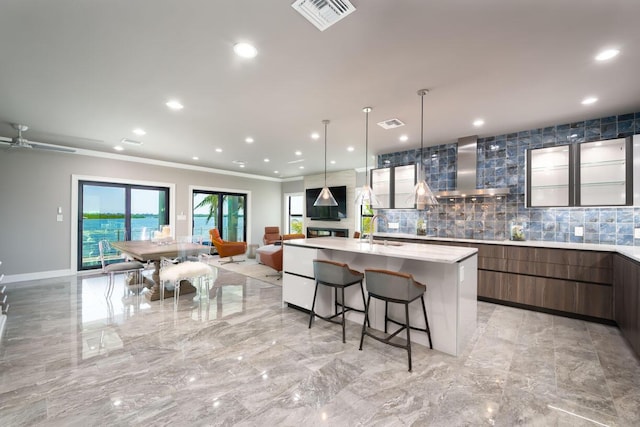 kitchen featuring wall chimney exhaust hood, sink, a kitchen island, and backsplash