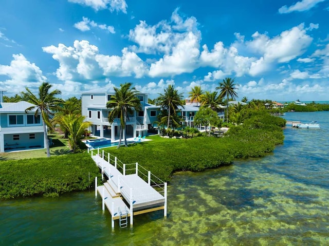 view of dock with a water view, a balcony, and a yard