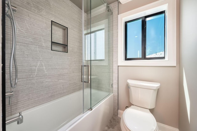 bathroom featuring combined bath / shower with glass door and toilet