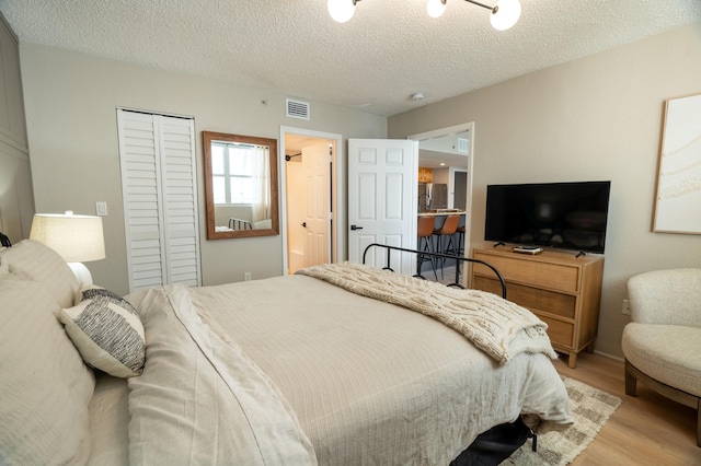 bedroom with light hardwood / wood-style flooring, a closet, and a textured ceiling