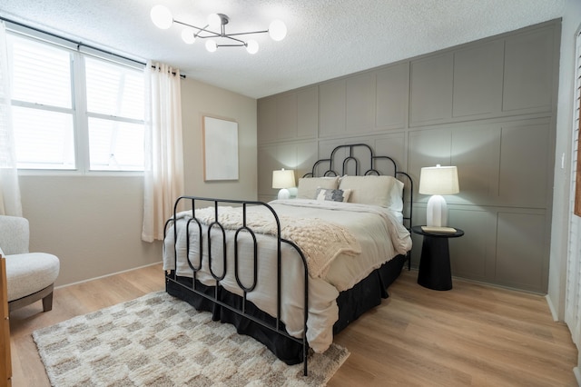 bedroom with a notable chandelier, a textured ceiling, and light hardwood / wood-style floors