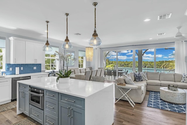 kitchen with appliances with stainless steel finishes, white cabinetry, light countertops, and decorative light fixtures