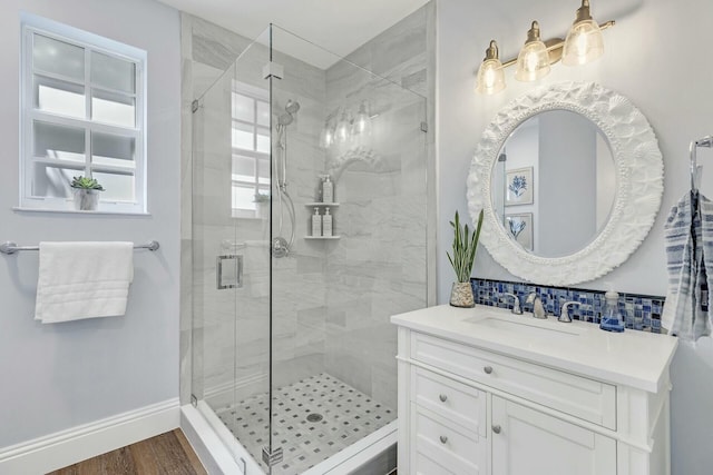 full bath with a stall shower, wood finished floors, vanity, and baseboards