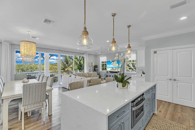 kitchen featuring open floor plan, light countertops, stainless steel oven, and visible vents