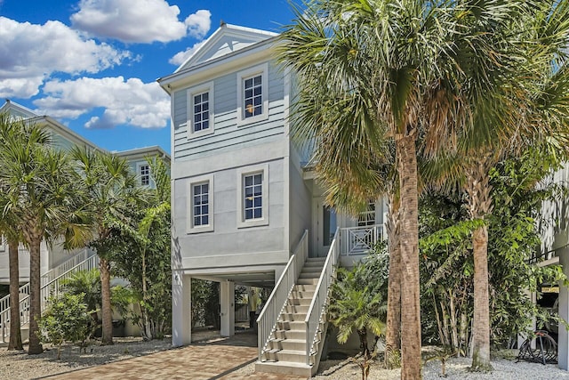 raised beach house with stairs, decorative driveway, and stucco siding