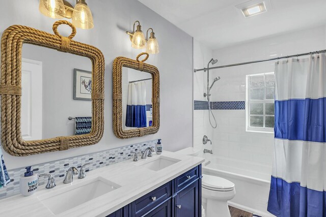 bathroom with toilet, double vanity, a sink, and shower / bath combo with shower curtain